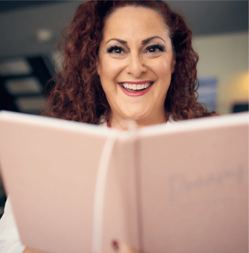 Happy woman reading a notebook